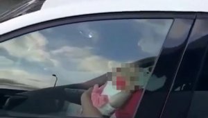 Kucağında bebek ile direksiyon sallayan sürücü kamerada